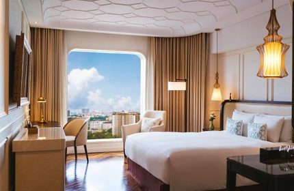 Hôtel des Arts Saigon MGallery Collection room. Gay-friendly hotel with city view, desk, chair, and bed. Saigon travel destination.