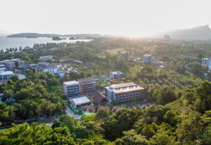 Aerial view of Hula Hula Resort, a gay-friendly hotel in Ao Nang, Thailand. Lush greenery surrounds the resort near the coast.