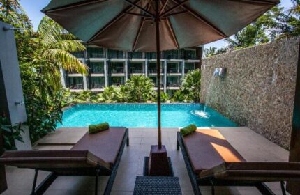 Hula Hula Resort Ao Nang pool view. Gay-friendly hotel with sun loungers, umbrella, and lush greenery. Perfect for gay travelers' relaxation.