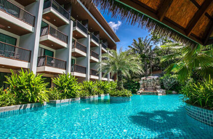 Hula Hula Resort Ao Nang pool view. Gay-friendly hotel with balconies, lush greenery, and a waterfall feature. Tropical paradise.