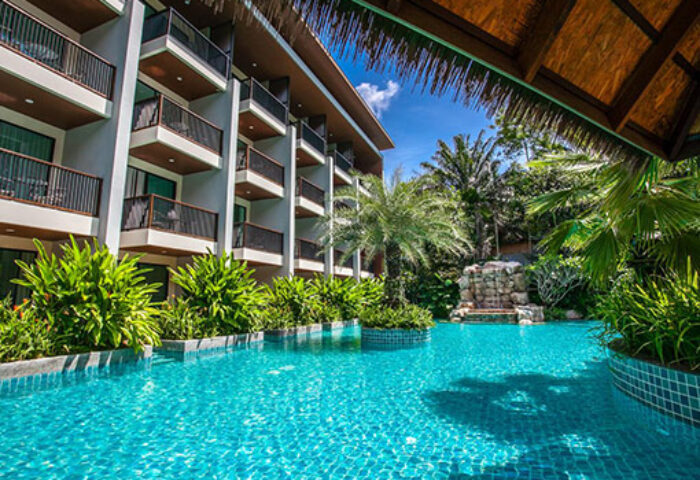 Hula Hula Resort Ao Nang pool view. Gay-friendly hotel with balconies, lush greenery, and a waterfall feature. Tropical paradise.