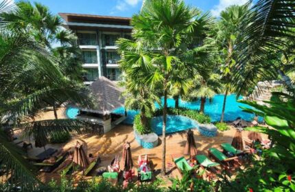 Hula Hula Resort Ao Nang, a gay-friendly hotel. View of the pool area with palm trees, sun loungers, and a bar. A tropical paradise.