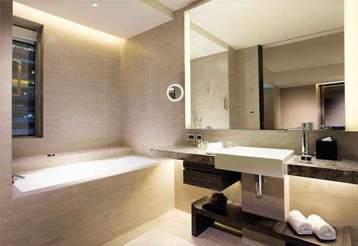 Bathroom at Humble House Taipei, a gay-friendly hotel. Features a bathtub, sink, illuminated mirror, and modern design. Ideal for gay travelers.