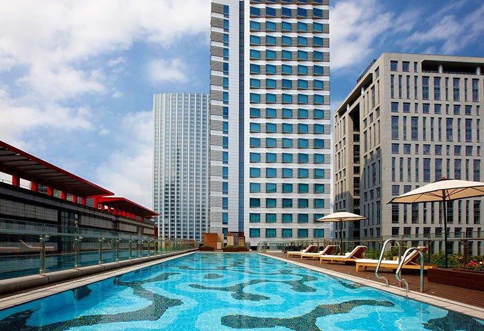 Humble House Taipei gay-friendly hotel pool view. Modern architecture, lounge chairs, and parasols create a relaxing urban oasis.