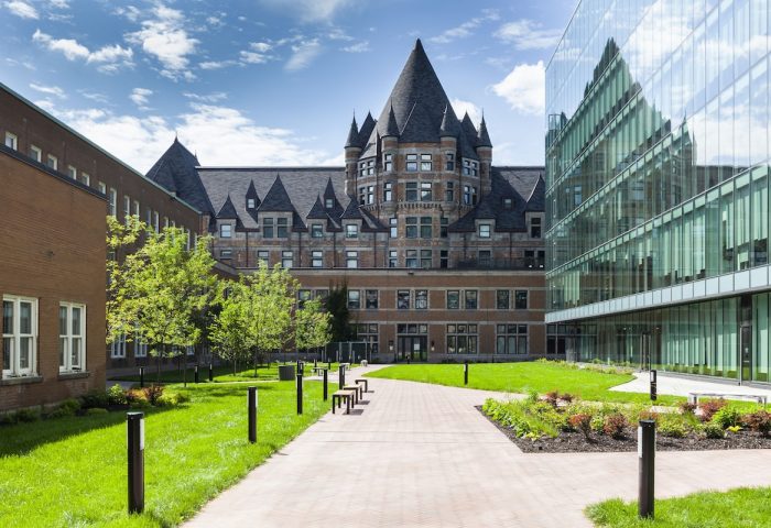Hyatt Centric Montreal, a gay-friendly hotel. Exterior view of the hotel with a modern glass building and an older building with a pointed roof.
