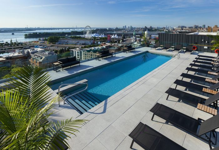 Rooftop pool at Hyatt Centric Montreal, a gay-friendly hotel. Lounge chairs surround the pool, with city views. Perfect for gay travel.