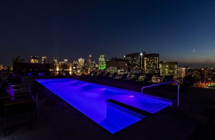 Hyatt Centric Montreal gay-friendly hotel rooftop pool at night. City skyline view. Ideal for gay travelers seeking luxury and vibrant nightlife.