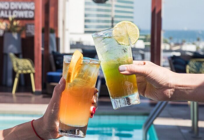 Cheers at Hyatt Centric The Pike Long Beach, a gay-friendly hotel. Cocktails by the pool offer a refreshing, inclusive vibe for gay travelers.