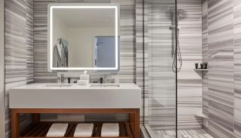 Hyatt Centric The Pike Long Beach gay-friendly hotel bathroom. Modern design with marble, glass shower, and illuminated mirror.