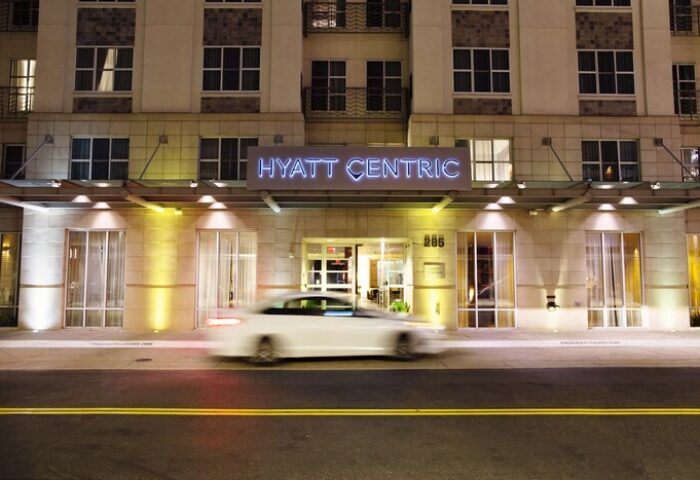 Hyatt Centric The Pike Long Beach entrance at night. Gay-friendly hotel with neon sign. Car passing by. Great location for LGBT travelers.