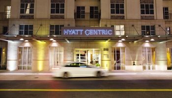 Hyatt Centric The Pike Long Beach entrance at night. Gay-friendly hotel with neon sign. Car passing by. Great location for LGBT travelers.