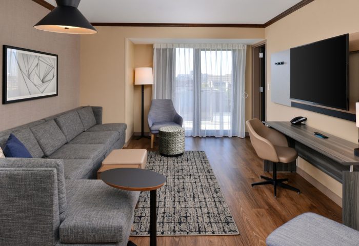 Hyatt Place Chicago/Wicker Park hotel room. Gay-friendly hotel featuring a gray sofa, desk, and TV. Modern interior design.