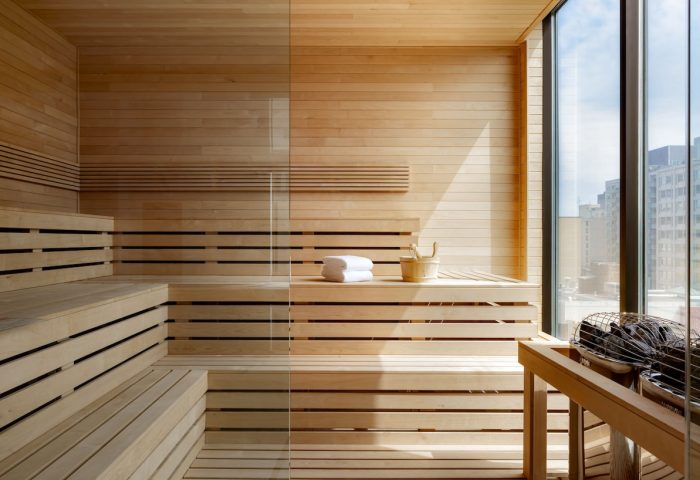 Sauna at Hyatt Place Montreal Downtown, a gay-friendly hotel. Features wooden benches, glass partition, towels, and a city view.