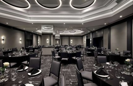 Elegant event space at Hyatt Place Montreal Downtown. Round tables with black linens, set for a formal dinner. Gay-friendly hotel venue.