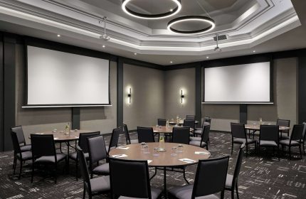 Meeting room at the gay-friendly Hyatt Place Montreal Downtown hotel. Tables, chairs, and projector screens for events.