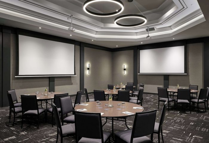 Meeting room at the gay-friendly Hyatt Place Montreal Downtown hotel. Tables, chairs, and projector screens for events.
