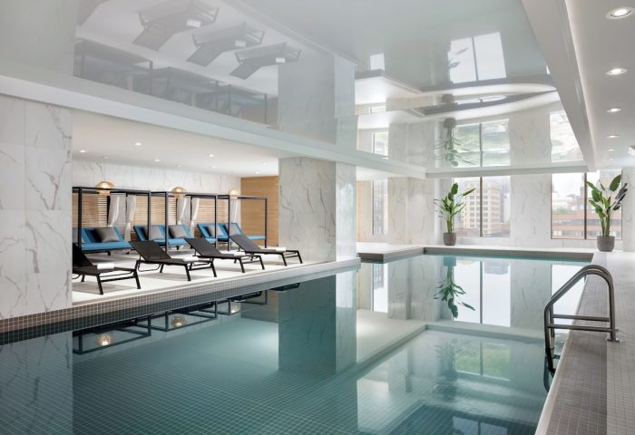 Indoor pool at the gay-friendly Hyatt Place Montreal Downtown hotel. Loungers, plants, and city views create a relaxing atmosphere.