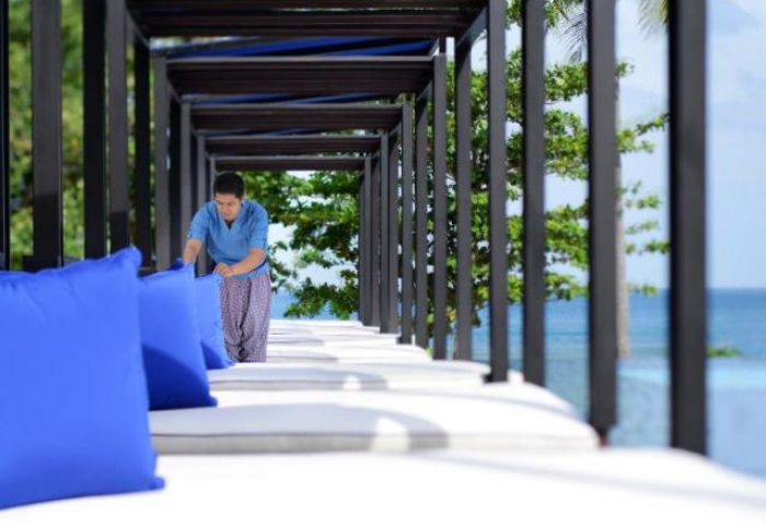 Hyatt Regency Phuket Resort detail. Staff member arranging blue pillows on a daybed. Gay-friendly hotel, Phuket travel advice.