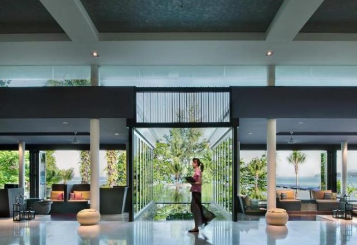 Lobby at Hyatt Regency Phuket Resort, a gay-friendly hotel. Woman walks past view of ocean. Modern design, luxury travel, Thailand.