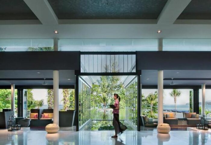 Lobby at Hyatt Regency Phuket Resort, a gay-friendly hotel. Woman walks past view of ocean. Modern design, luxury travel, Thailand.