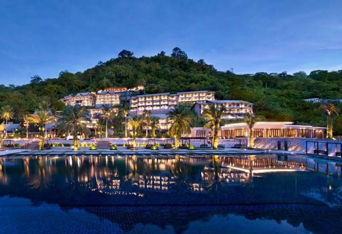 Hyatt Regency Phuket Resort, a gay-friendly hotel. Evening view of the resort, pool reflecting lights, and lush hillside. Gay travel in Phuket.