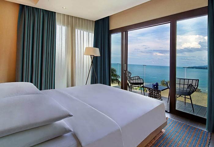 Hyatt Regency Phuket Resort room with ocean view. Gay-friendly hotel with balcony, chairs, and table. Relaxing travel destination for gay men.