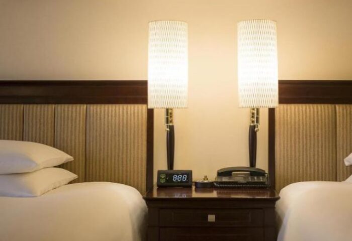 Hyatt Regency Tokyo hotel room with twin beds. Nightstand with lamps, phone, and alarm clock. Gay-friendly hotel for gay men travel advice.