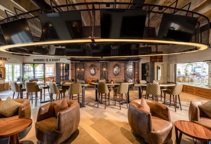 Hyatt Zilara Cancun's stylish bar area. This gay-friendly hotel features brown leather chairs, high-top tables, and a unique overhead TV display.