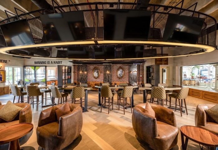 Hyatt Zilara Cancun's stylish bar area. This gay-friendly hotel features brown leather chairs, high-top tables, and a unique overhead TV display.