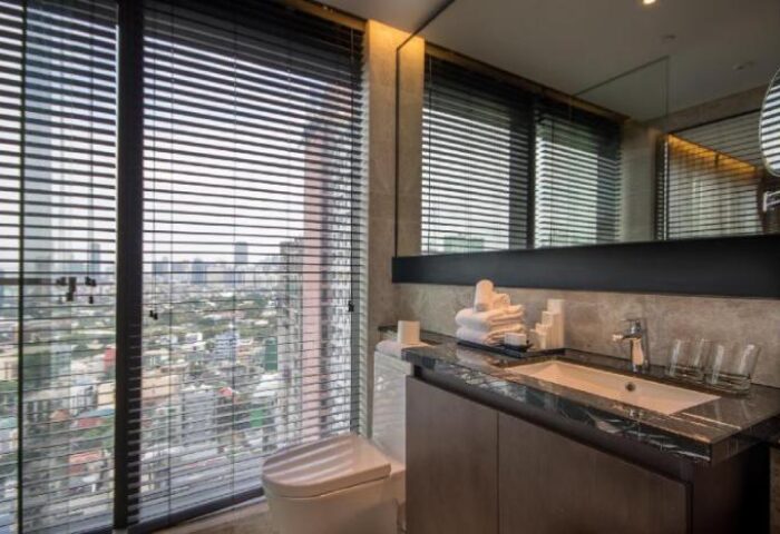 Bathroom in I'M Hotel, a gay-friendly hotel. Sink, toilet, and a large window with city views. Modern design. Gay travel.