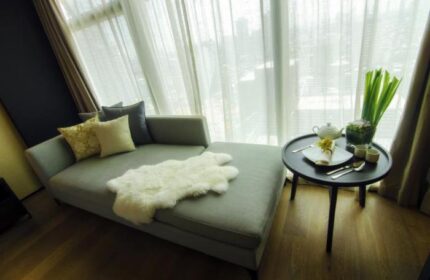 I'M Hotel: Gay-friendly hotel room with couch, pillows, sheepskin rug, and tea service on a table by a window. Modern, stylish interior.