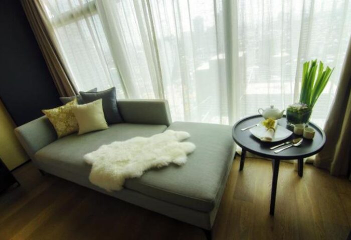 I'M Hotel: Gay-friendly hotel room with couch, pillows, sheepskin rug, and tea service on a table by a window. Modern, stylish interior.