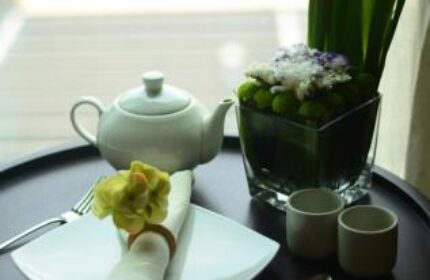I'M Hotel gay-friendly hotel: Table setting with teapot, plate, cutlery, and floral arrangement. A luxury hotel experience for gay travelers.