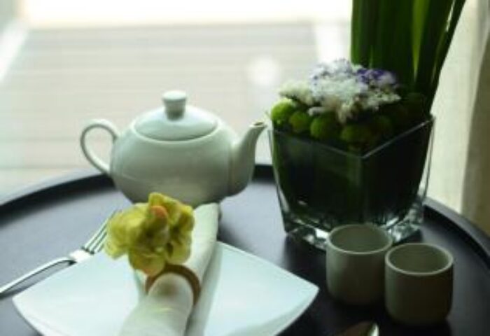 I'M Hotel gay-friendly hotel: Table setting with teapot, plate, cutlery, and floral arrangement. A luxury hotel experience for gay travelers.