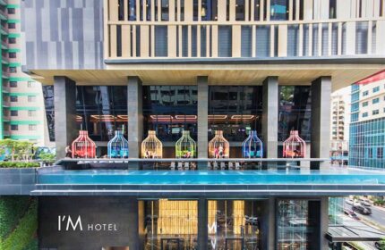 I'M Hotel, a gay-friendly hotel. Facade view with colorful birdcage structures on the pool deck. Modern architecture in Makati, Philippines.
