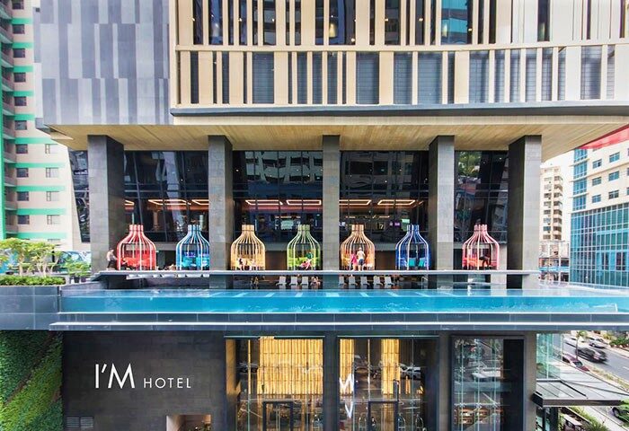 I'M Hotel, a gay-friendly hotel. Facade view with colorful birdcage structures on the pool deck. Modern architecture in Makati, Philippines.