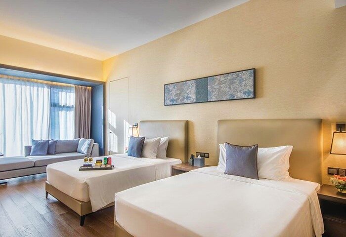 I'M Hotel's gay-friendly room: two beds, sofa, and modern decor. A welcoming space for gay travelers seeking comfort and style.