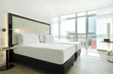 INNSiDE Milano Torre Galfa gay-friendly hotel room. Two twin beds with white linens, large window with city view. Modern, bright, and clean design.