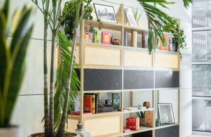 INNSiDE Milano Torre Galfa's stylish interior. Bookshelf with books, plants, & decor. Gay-friendly hotel design, inviting atmosphere.