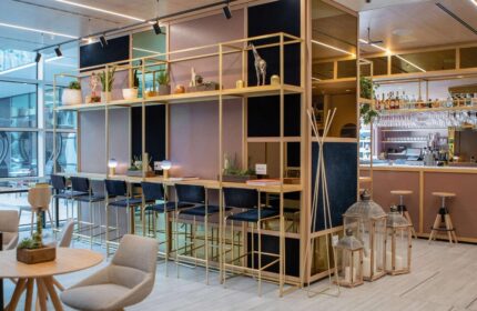 INNSiDE Milano Torre Galfa's stylish bar area. This gay-friendly hotel features modern design, bar stools, shelving, and a relaxed atmosphere.