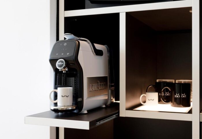 INNSiDE Milano Torre Galfa gay-friendly hotel room detail: Lavazza coffee maker and mugs on a shelf. Modern design, perfect for gay travelers.