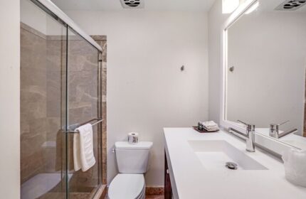 INNdulge Iconic Gay Men's Resort bathroom. Modern design with a glass shower, white counter, & toilet. Gay-friendly hotel for men's travel.