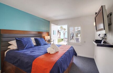 INNdulge Iconic Gay Men's Resort room. Blue bedding, orange runner, and TV. Door to patio. Gay-friendly hotel for gay men travelers.