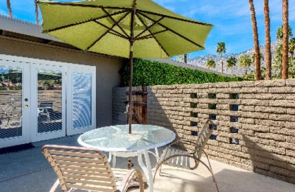 INNdulge Iconic Gay Men's Resort patio with table, chairs, and umbrella. Gay-friendly hotel outdoor space, perfect for relaxing. Palm Springs travel.