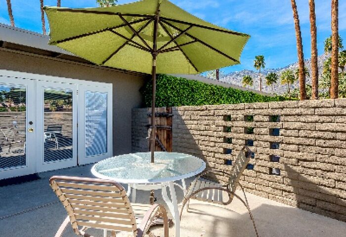 INNdulge Iconic Gay Men's Resort patio with table, chairs, and umbrella. Gay-friendly hotel outdoor space, perfect for relaxing. Palm Springs travel.