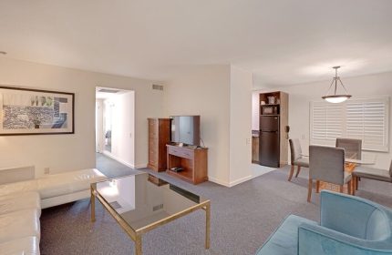 INNdulge Iconic Gay Men's Resort suite interior. Living room with couch, TV, and coffee table. Dining area and kitchenette. Gay-friendly hotel.