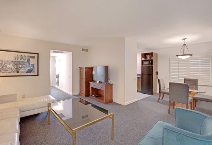INNdulge Iconic Gay Men's Resort suite interior. Living room with couch, TV, and coffee table. Dining area and kitchenette. Gay-friendly hotel.