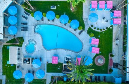 Aerial view of INNdulge, an iconic gay men's resort. Pool, umbrellas, lounge chairs, & cabanas create a relaxing, gay-friendly hotel vibe.