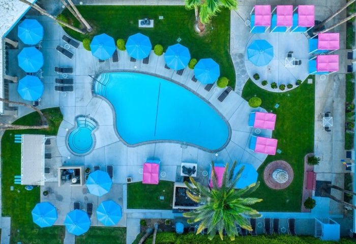 Aerial view of INNdulge, an iconic gay men's resort. Pool, umbrellas, lounge chairs, & cabanas create a relaxing, gay-friendly hotel vibe.
