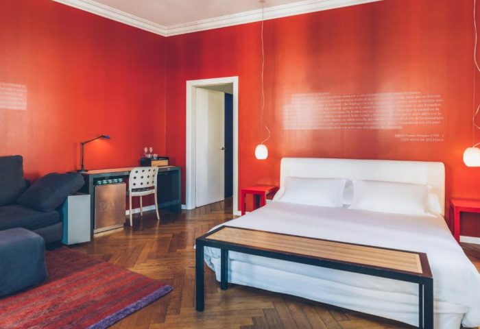 Iberostar Las Letras Gran Vía room. Pet-friendly, gay-friendly hotel with red walls, double bed, desk, sofa, and parquet floor. Madrid, Spain.